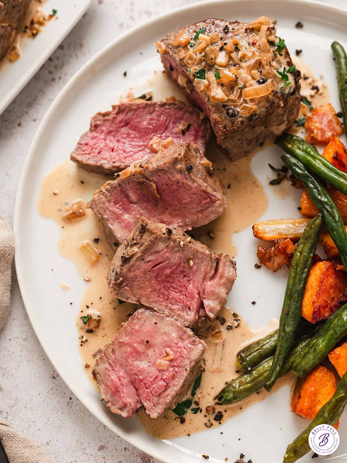 Sliced beef tenderloin on a plate with green beans