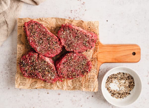 Seasoned beef tenderloin steaks on a cutting board