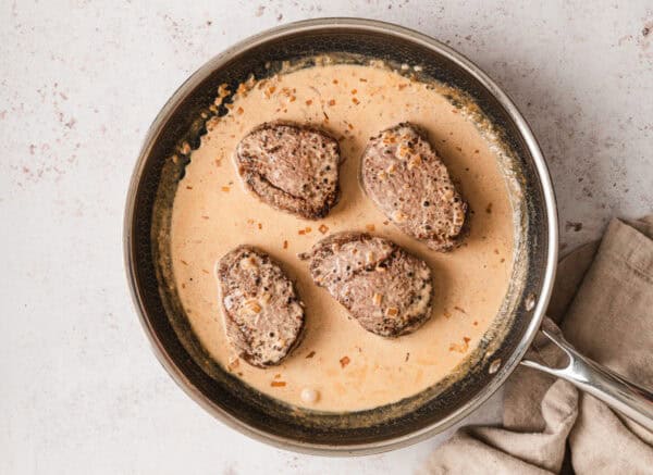 Beef tenderloin with peppercorn cream sauce in a skillet