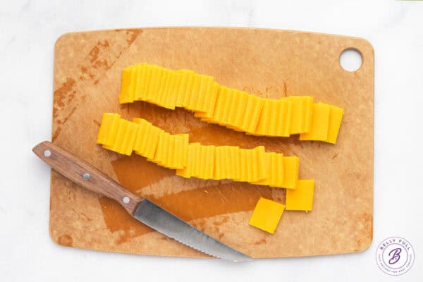 Cheddar cheese sliced on a cutting board