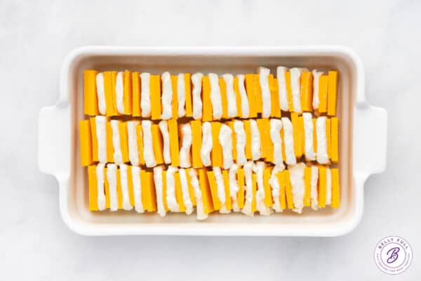 Sliced of cheddar cheese and cream cheese in a baking dish