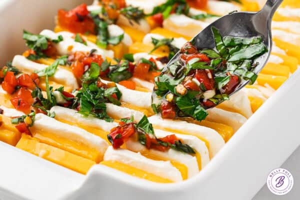 Marinade being spooned over sliced cheese in a baking dish