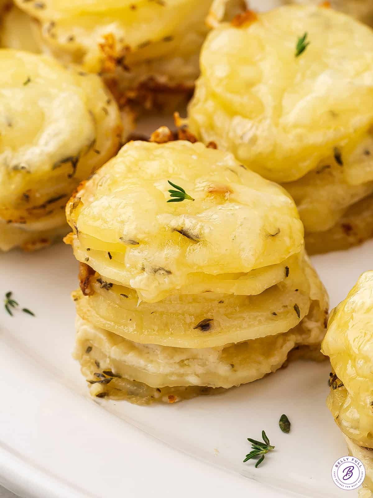 close up of potato stack with melted cheese and chopped thyme