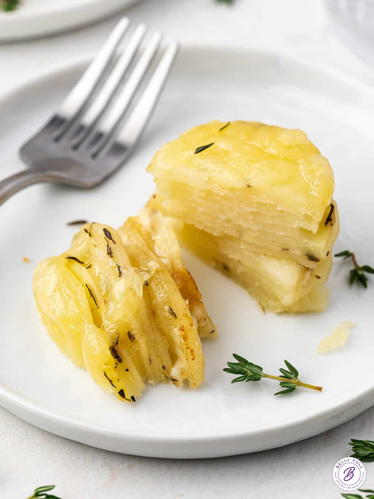 stack of thinly sliced potatoes with melted cheese sliced in half on plate