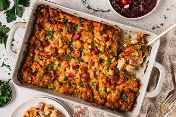 baked ham and gruyere stuffing in casserole dish with serving spoon