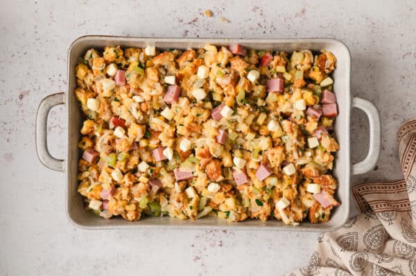 Unbaked ham and gruyere stuffing spread on a pan