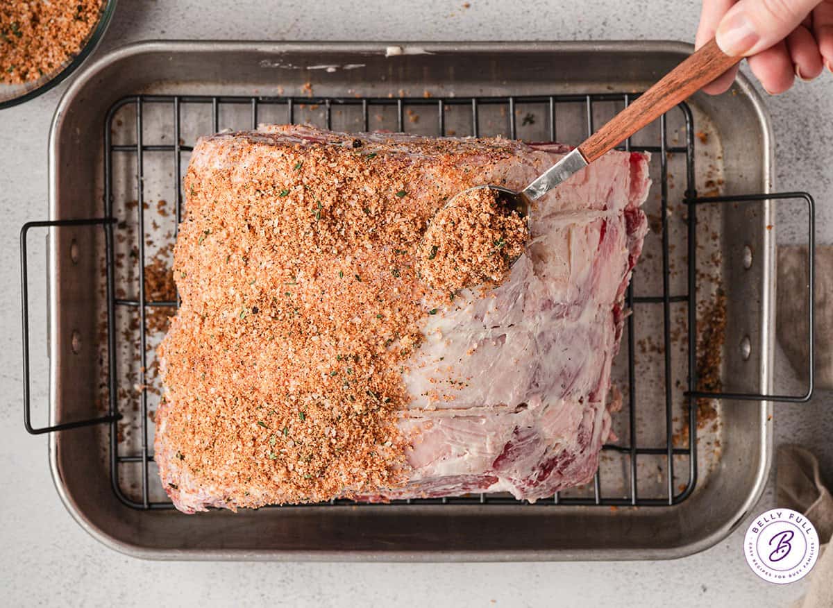 Prime rib rub being applied to a prime rib.