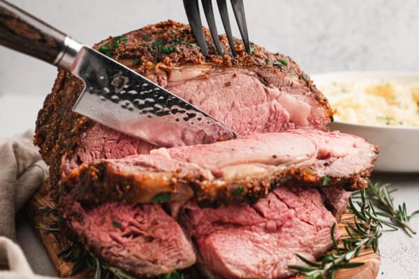 A knife slicing a prime rib roast.