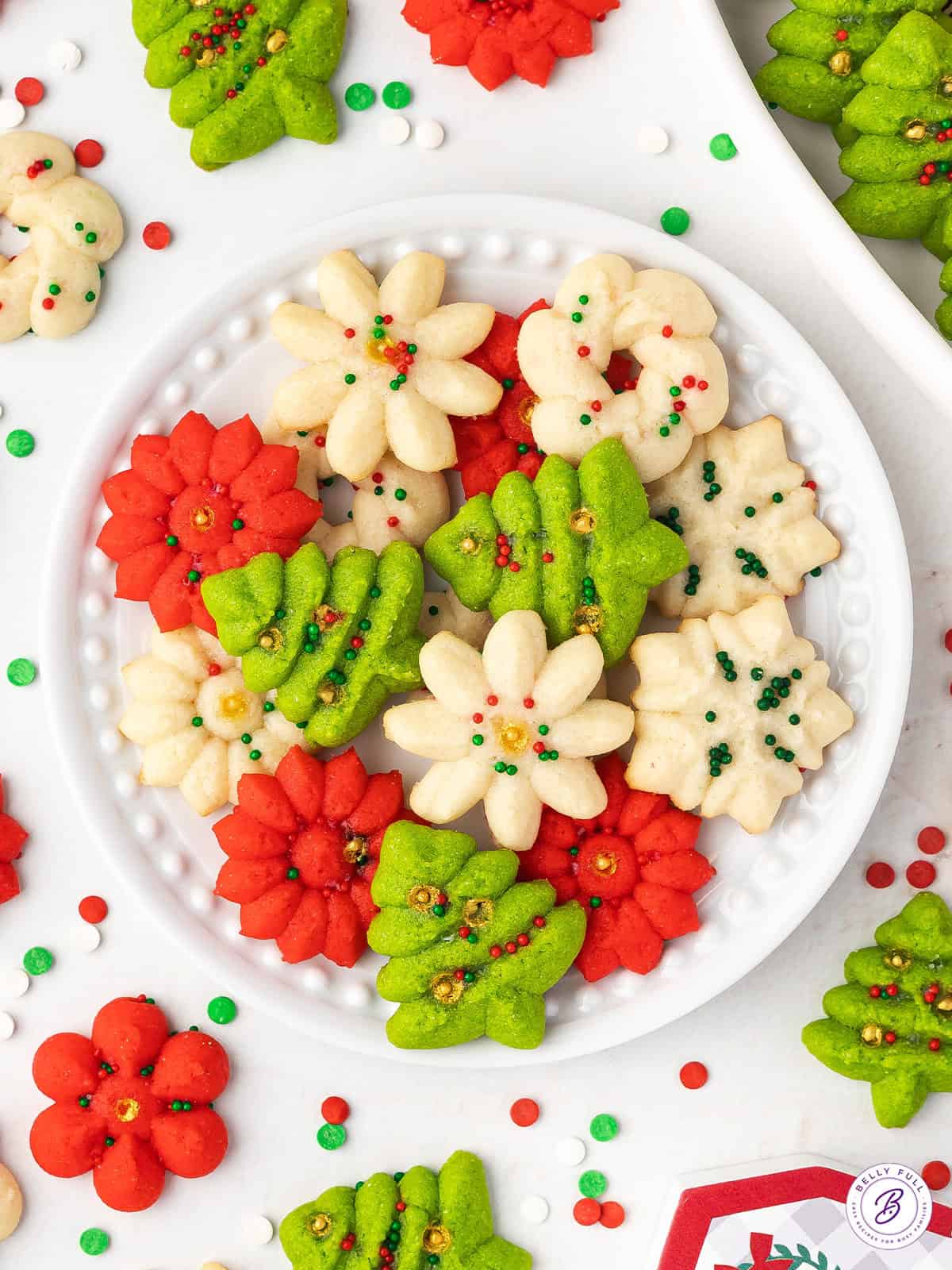 Overhead view of Christmas spritz cookies on a white plate.