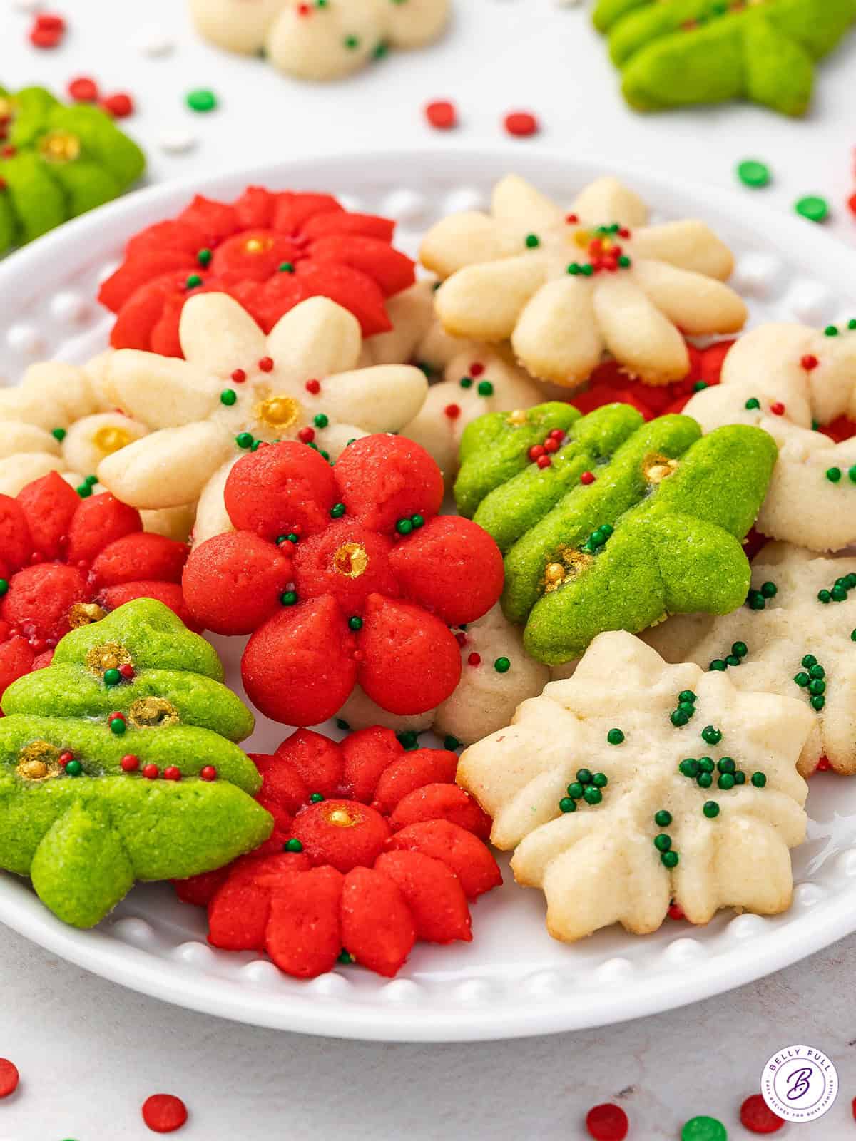 Side view of Christmas spritz cookies on a white plate.