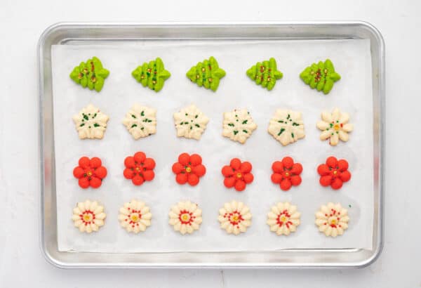 Freshly baked spritz cookies on a parchment lined baking sheet.