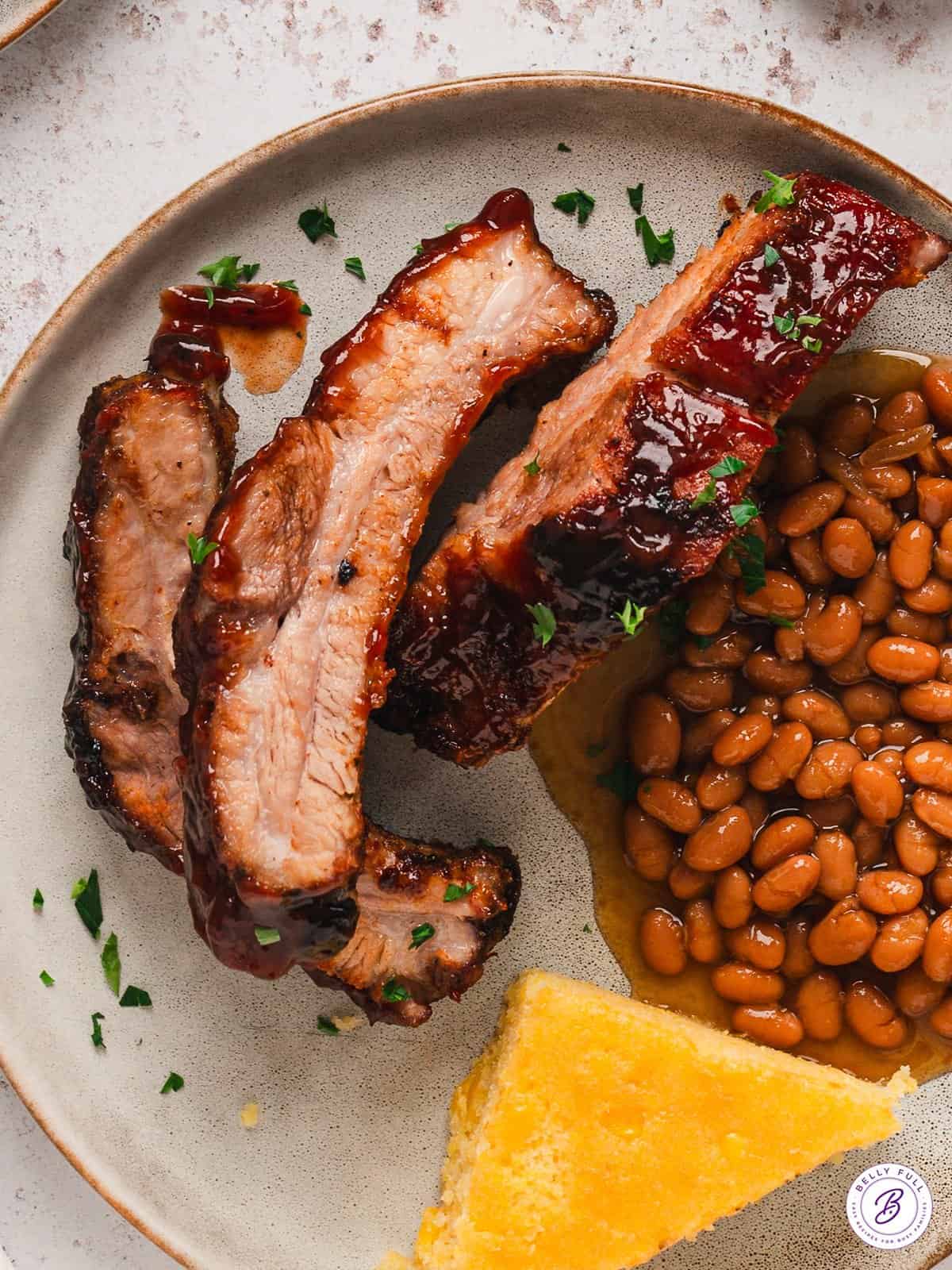 Baked baby back ribs on a plate with baked beans