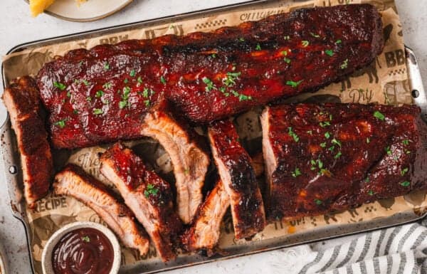 Baked baby back ribs being sliced on a cutting board