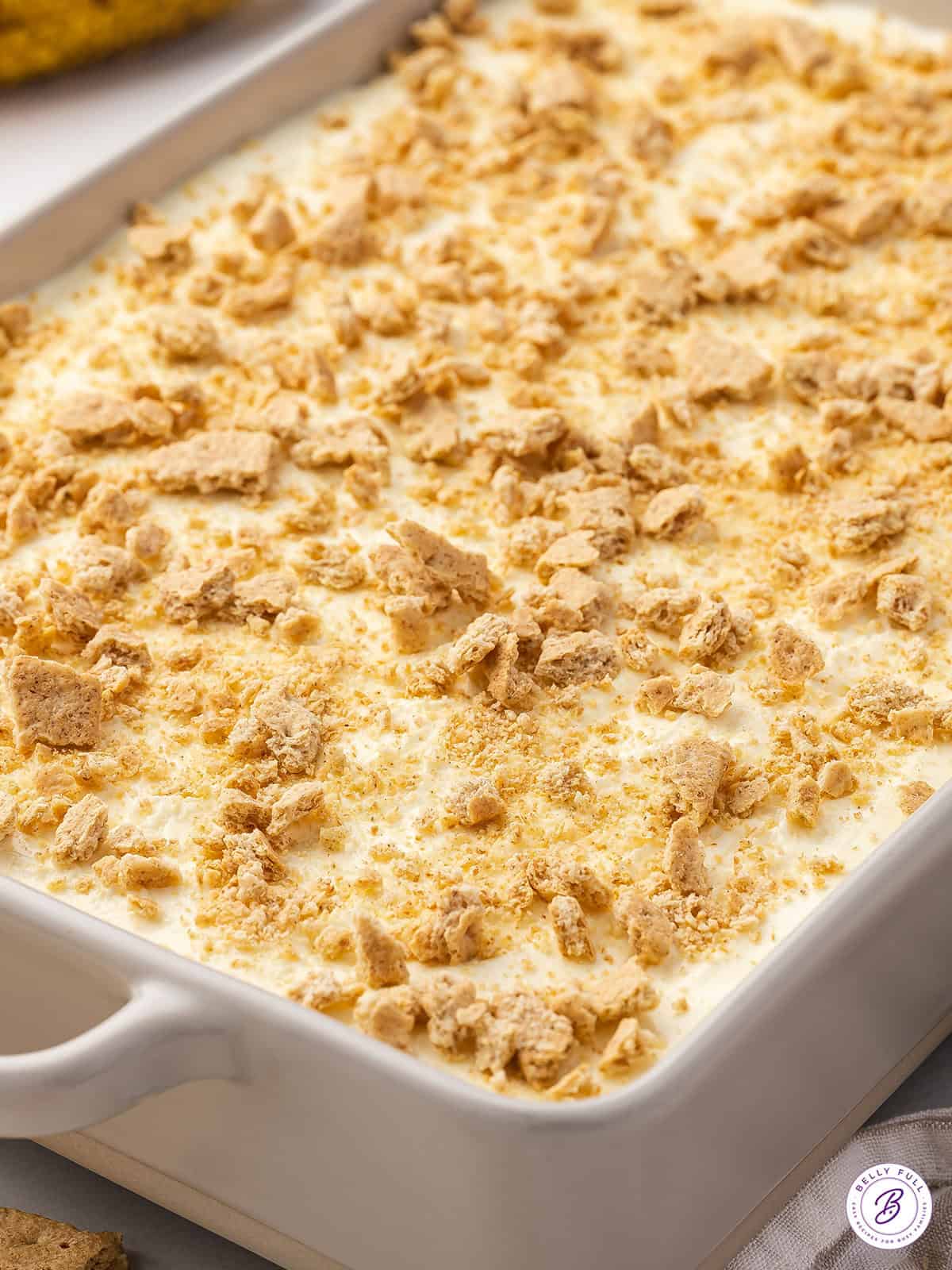 Banana Cream Lush with crushed graham crackers on top uncut in white casserole dish