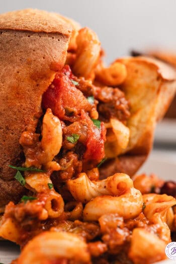 Close up of a chili mac stuffed popover with the chili mac spilling out