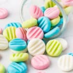 pastel colored cream cheese mints falling out of glass jar