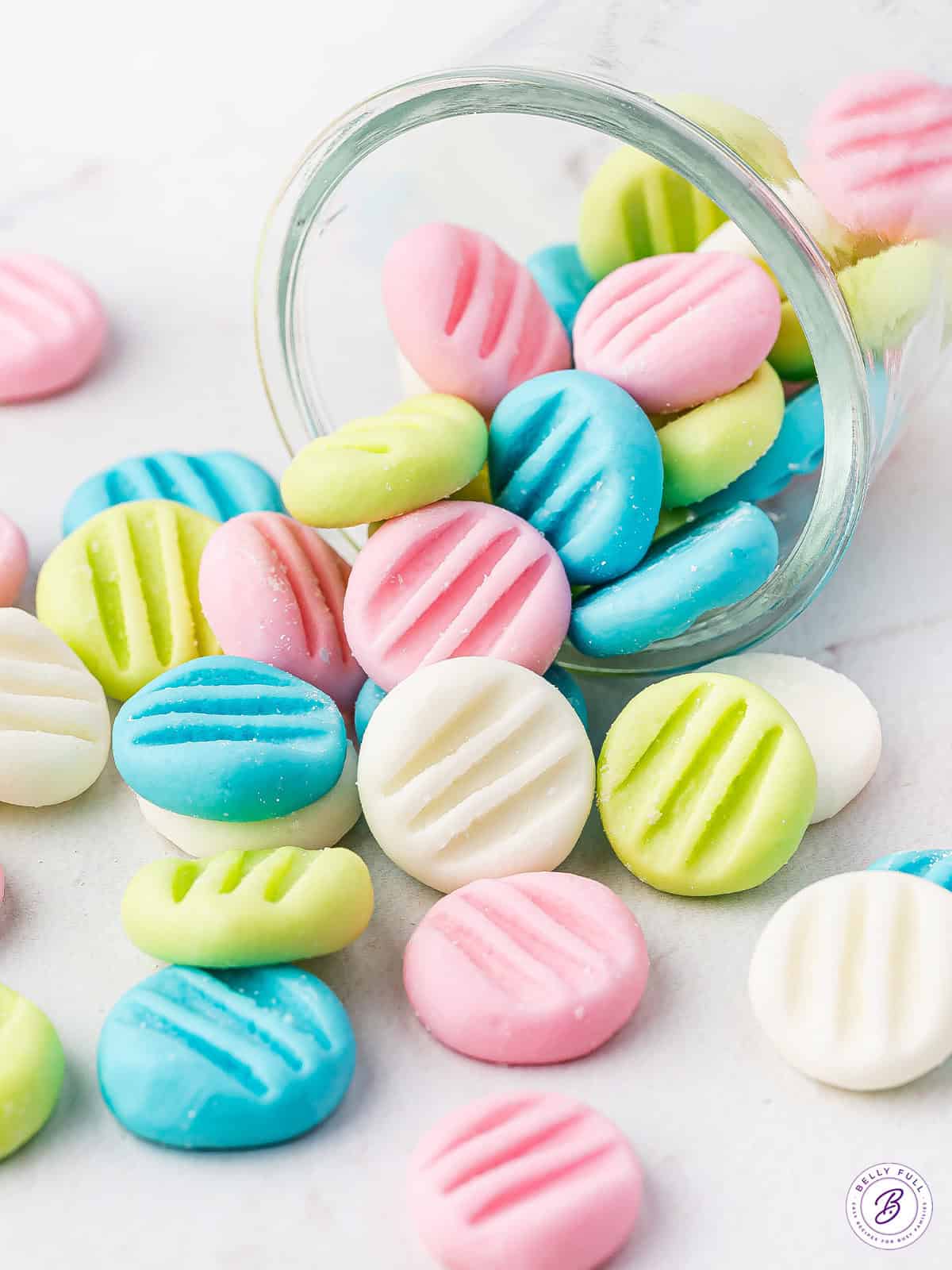 pastel colored cream cheese mints falling out of glass jar