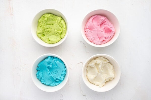 4 separate bowls with dyed cream cheese mint dough, colored green, pink, blue, and white