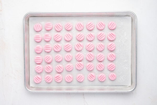 baking tray with rows of pink cream cheese button mints on top of parchment paper