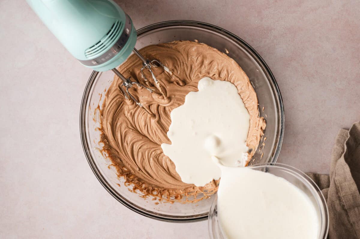 white whipped cream being poured into mocha flavored whipped mascarpone