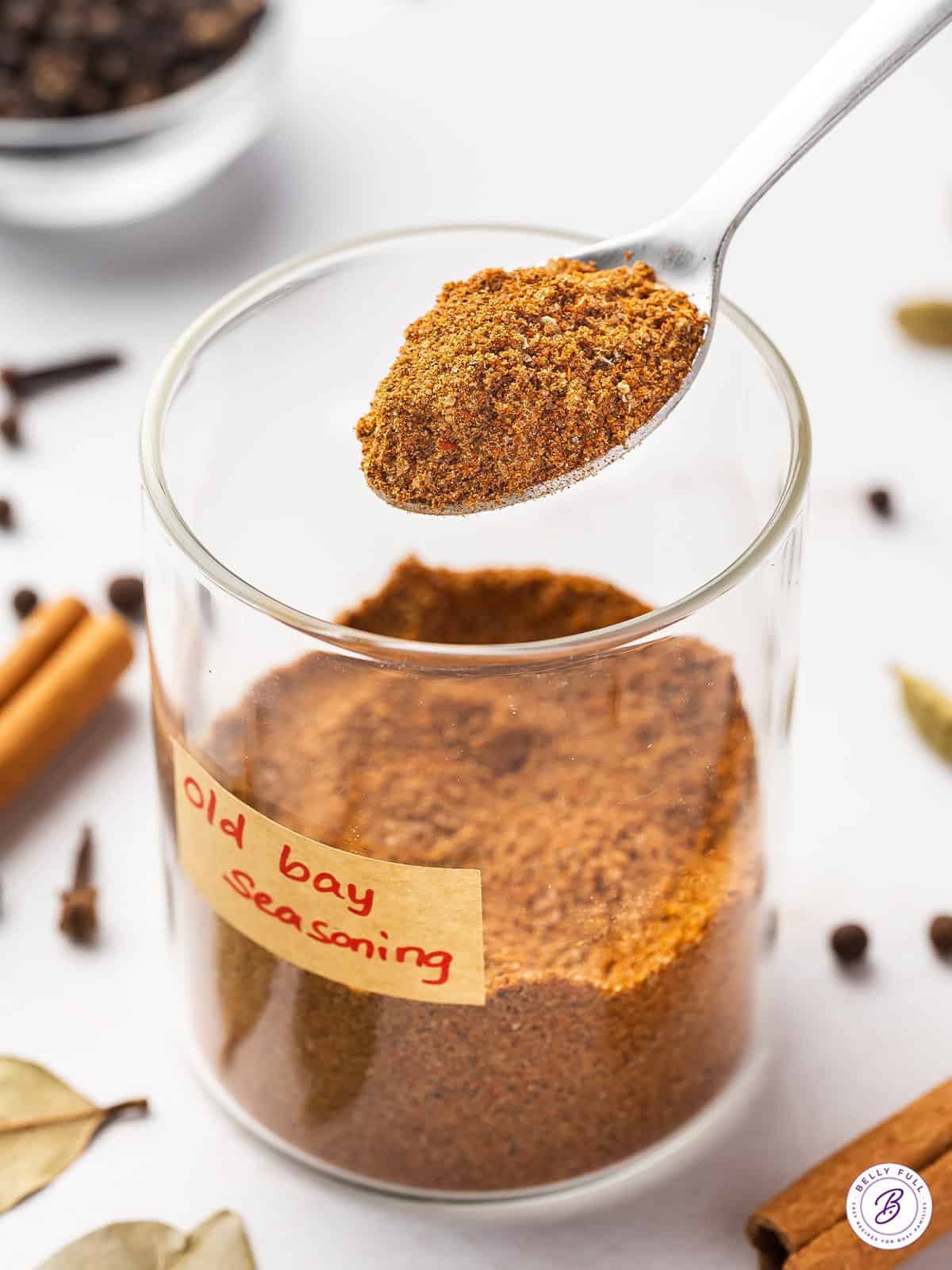 A spoon of Old Bay seasoning over a glass jar