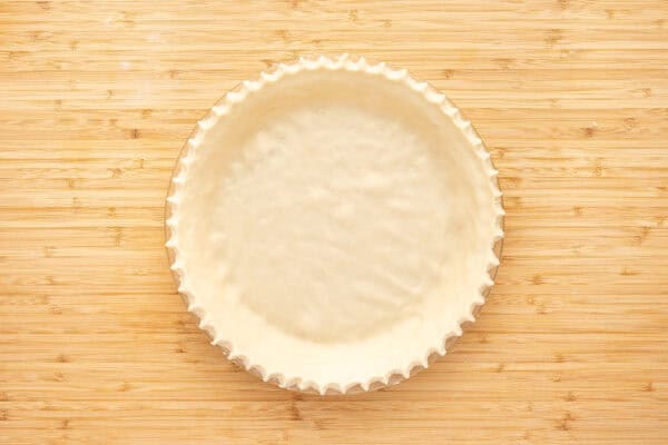 unbaked pie crust dough in pie plate with crimped edges