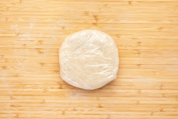 round disk of pie crust dough wrapped in plastic wrap