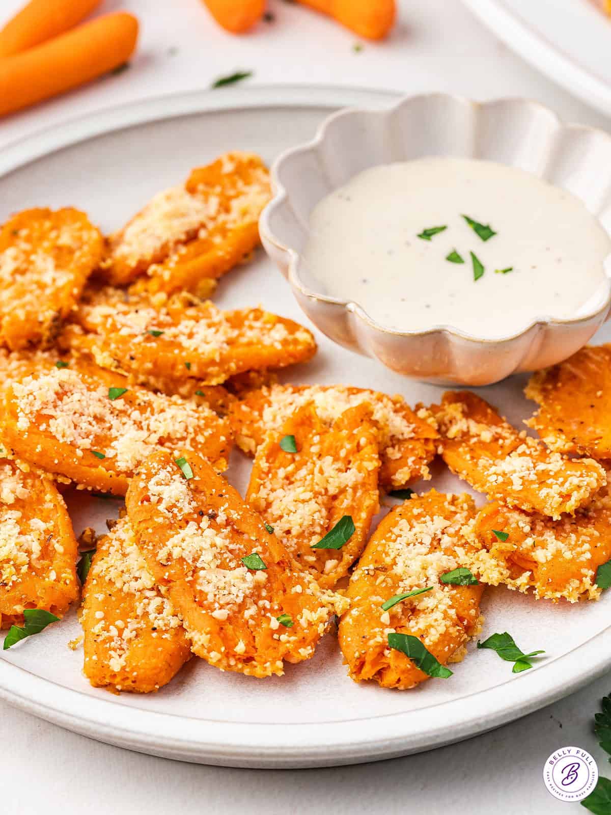 Smashed carrots on a plate with a bowl of ranch dressing