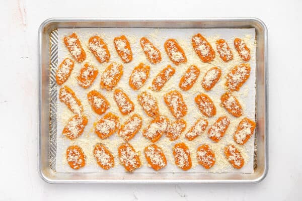 Unbaked parmesan smashed carrots on a baking sheet