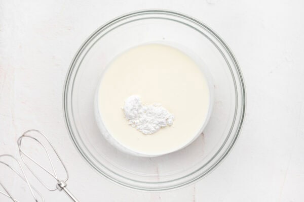 heavy cream and powdered sugar in glass mixing bowl