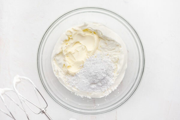 whipped cream, mascarpone cheese, and powdered sugar in glass mixing bowl