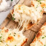 Pieces of chicken alfredo French bread pizza pulled apart with cheese stringing between them