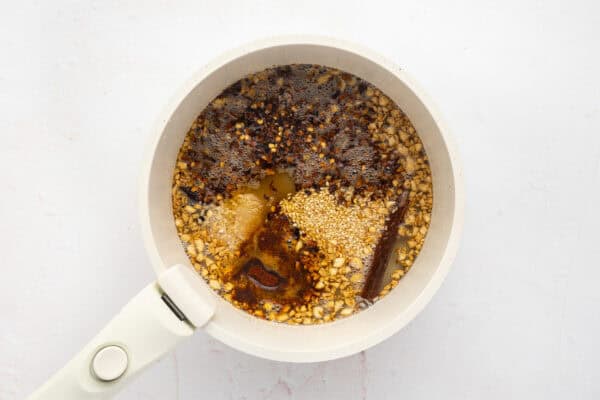 Toasted sesame seeds and spices added to sauteed garlic in a pan