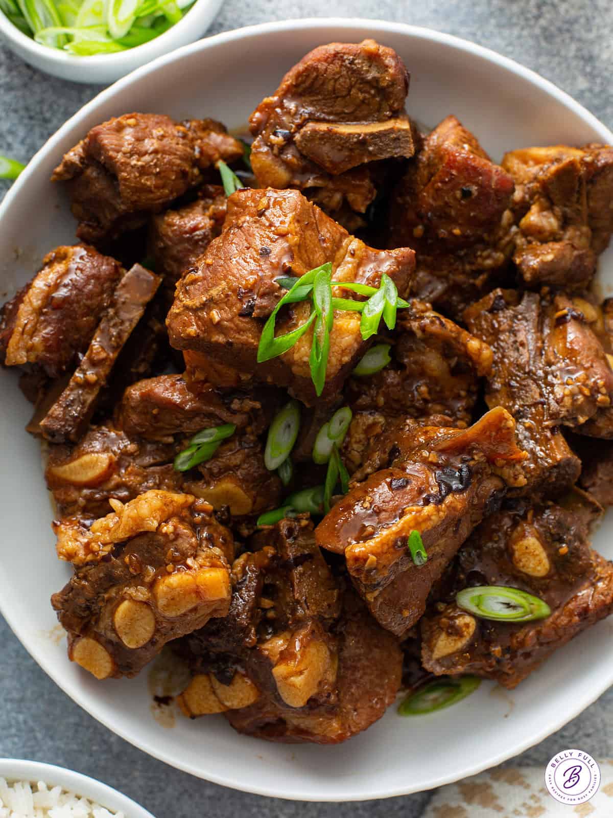 close up overhead Chinese pork spare ribs in a bowl with diced scallions