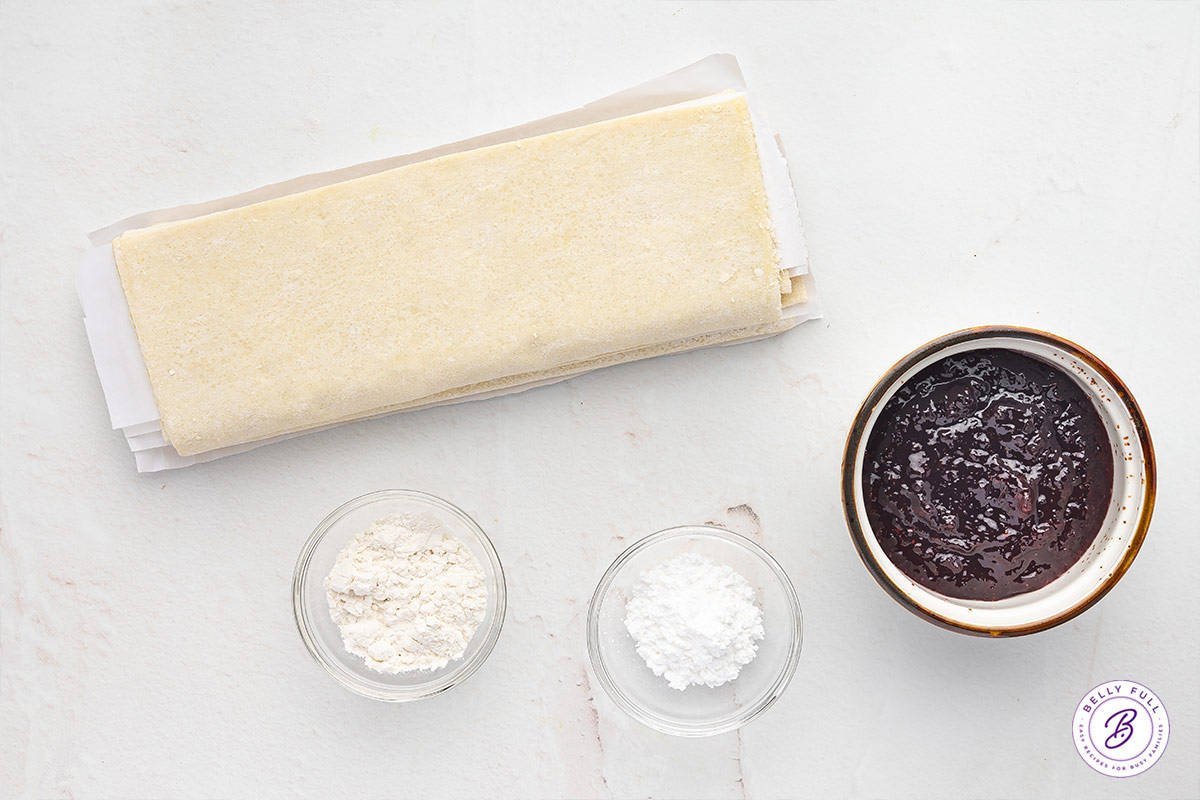 Overhead view of ingredients needed to make jam puff pastry rolls