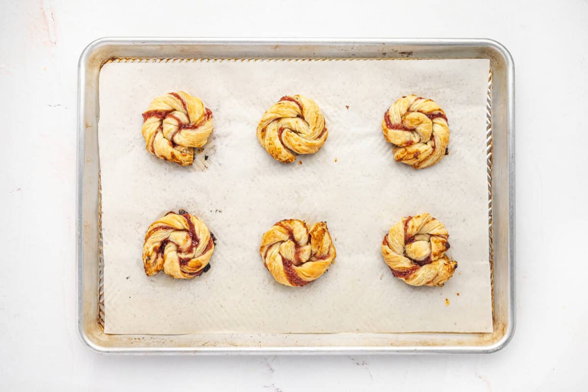 Baked jam puff pastry rolls on a baking sheet