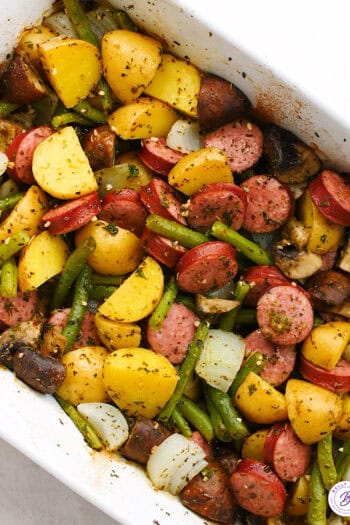 overhead baked sliced kielbasa, mushrooms, onion, and green beans in casserole dish