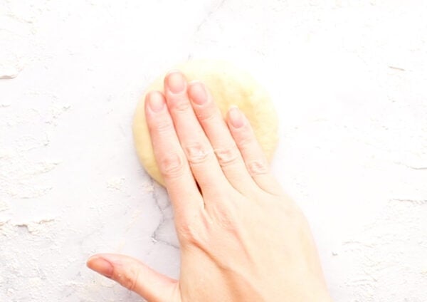 roll of dough being flattened with hand