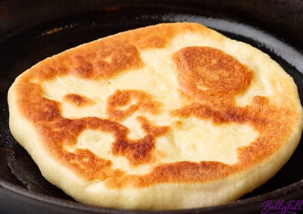 golden naan bread in cast iron skillet