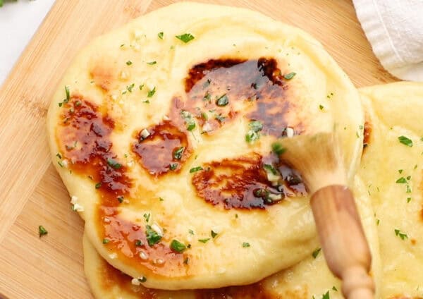 butter being basted onto warm naan bread