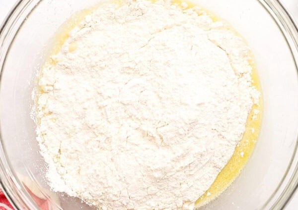 flour in glass bowl on top of egg and yeast mixture