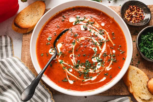 Overhead view of roasted red pepper soup, topped with cream and fresh parsley.