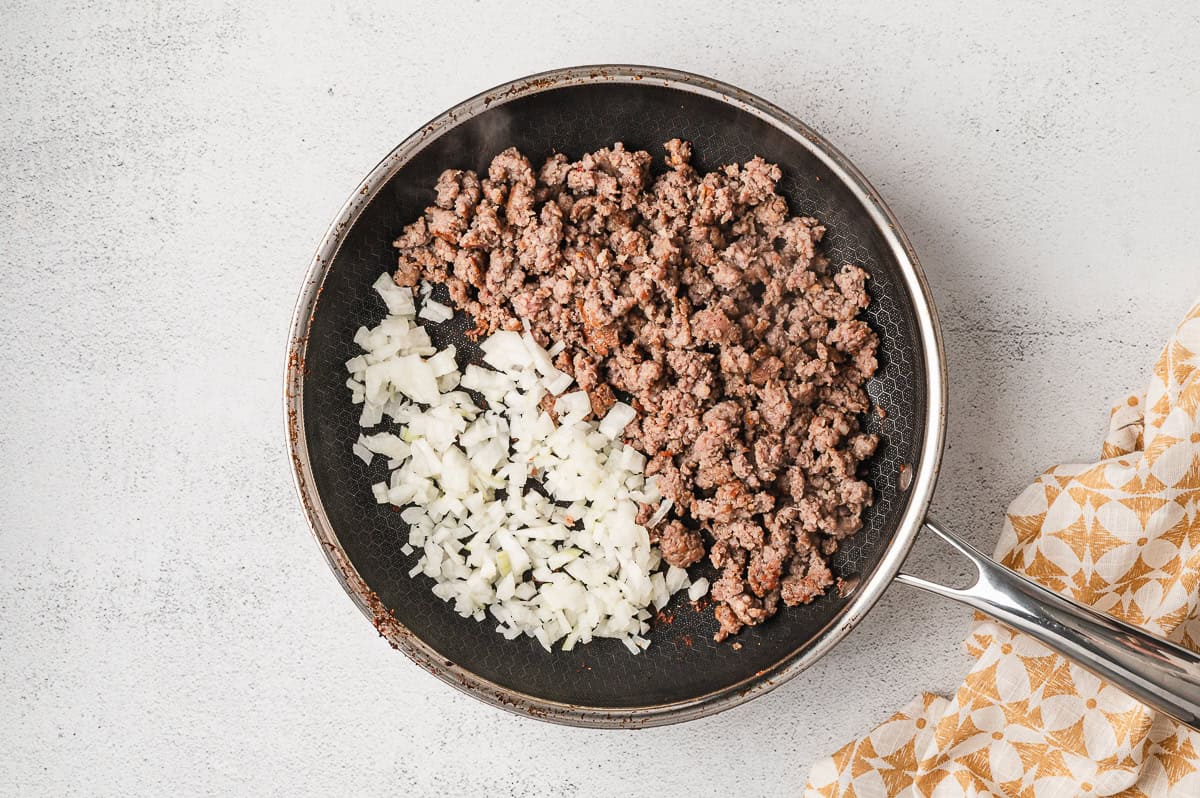 Crumbled sausage and onions in a frying pan