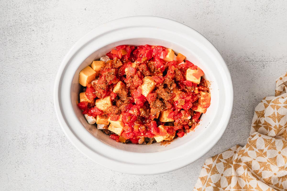 Rotel poured over cubes of cheese in a crockpot