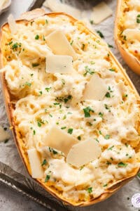 half of a roasted spaghetti squash mixed with alfredo sauce, garnished with parsley