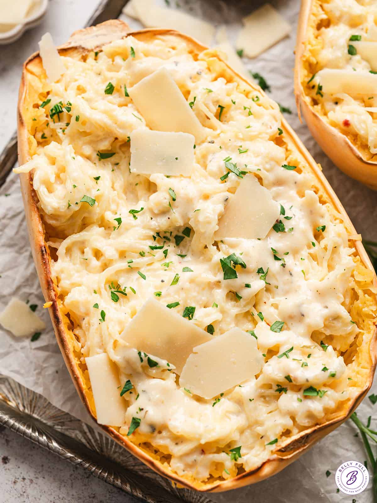 half of a roasted spaghetti squash mixed with alfredo sauce, garnished with parsley