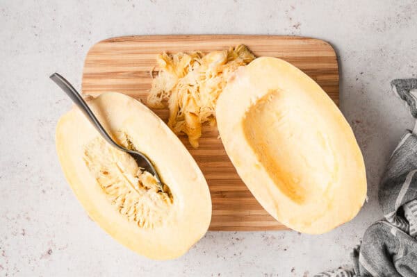 2 raw halves of spaghetti squash with seeds removed on cutting board