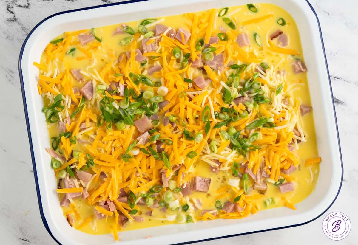 unbaked egg custard, cheese, and diced ham in casserole dish