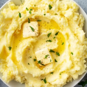 overhead bowl of creamy fluffy mashed potatoes with pats of butter