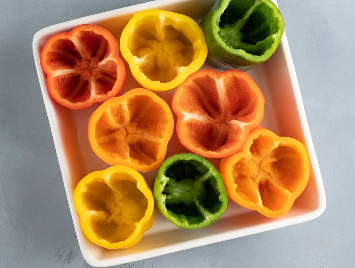 hollowed out green, red, yellow, and orange bell peppers in casserole dish
